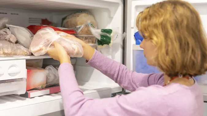 Teenager putting meat in a freezer stock photo