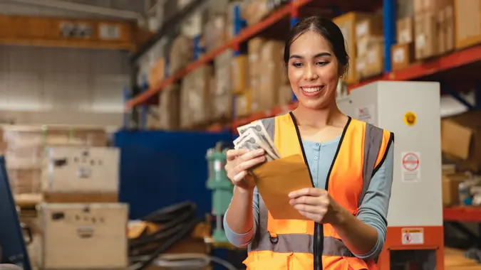 Worker employee recieve salary with working overtime bonus money payday work in factory warehouse.