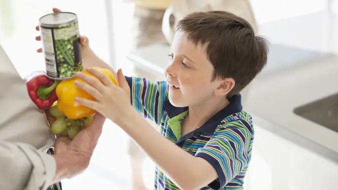 Boy stacking food into grandfather stock photo