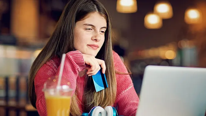 A teenage girl is shopping online in a cafeteria.