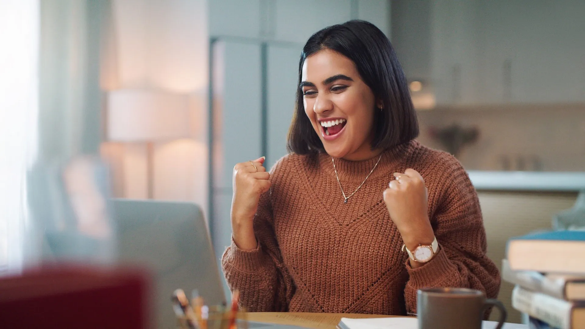 Shot of a young woman cheering while using a laptop to study at home stock photo