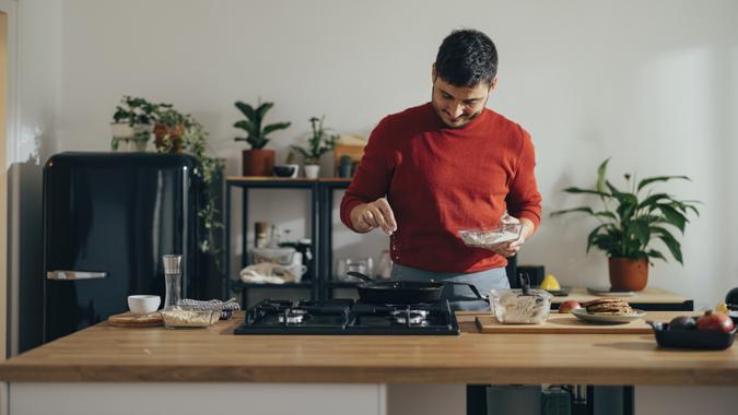 Handsome cheerful man preparing a meal in the kitchen.