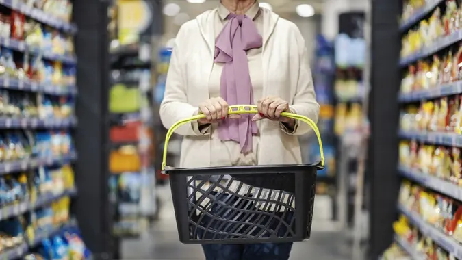 Cropped photo of senior woman holding empty shopping basket during economic crisis.