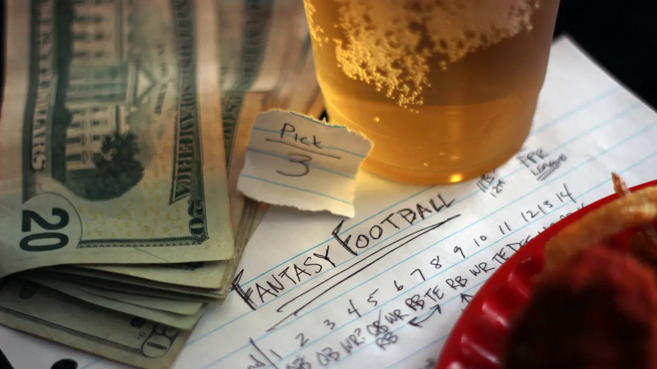 Montage of fantasy football draft elements which include draft notes, pick number, league information, money, food and beverages.