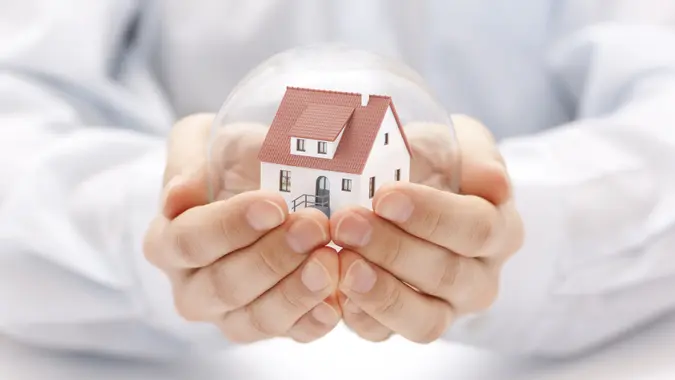 Crystal ball with house in hands stock photo