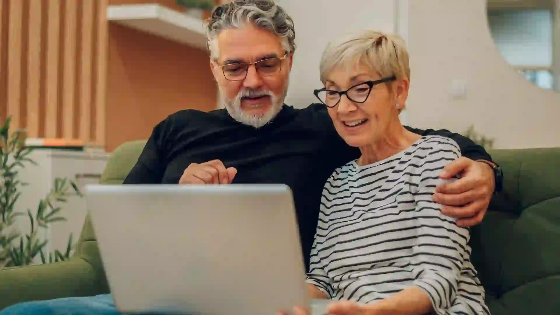 Senior couple using laptop while sitting on a couch at home stock photo