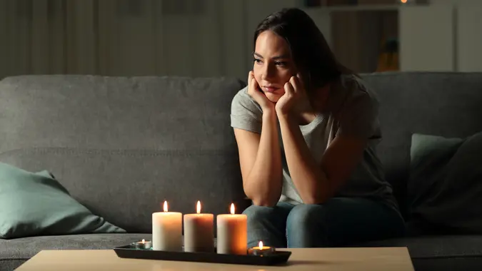 Frustrated woman sitting at home during a blackout sitting on a couch in the living room at home.