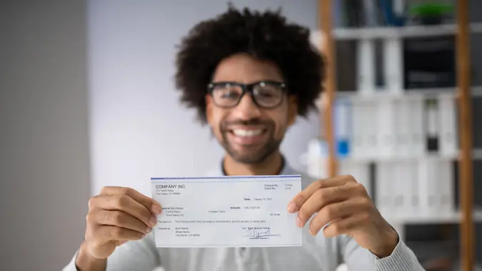 Midsection Of Smiling Businessman Holding Cheque In Office.