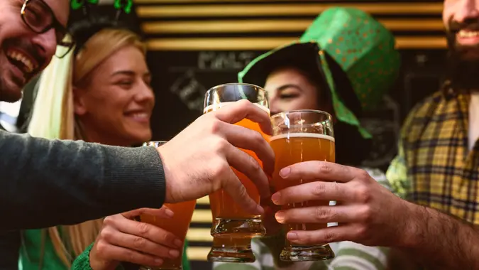 Smiling young people drinking craft beer in pub on St Patrick's Day holiday.