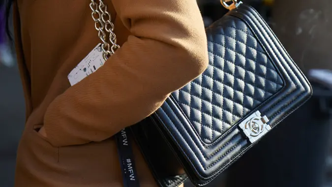 MILAN - JANUARY 14: Woman with black Chanel leather bag with silver chain and beige coat before MSGM fashion show, Milan Fashion Week street style on January 14, 2018 in Milan.