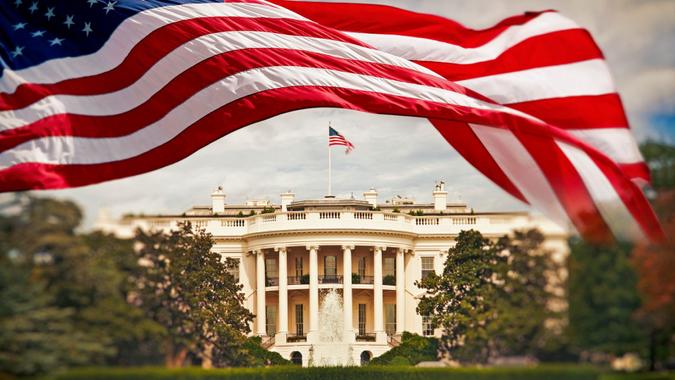 The White House in Washington DC with waving United States flag.