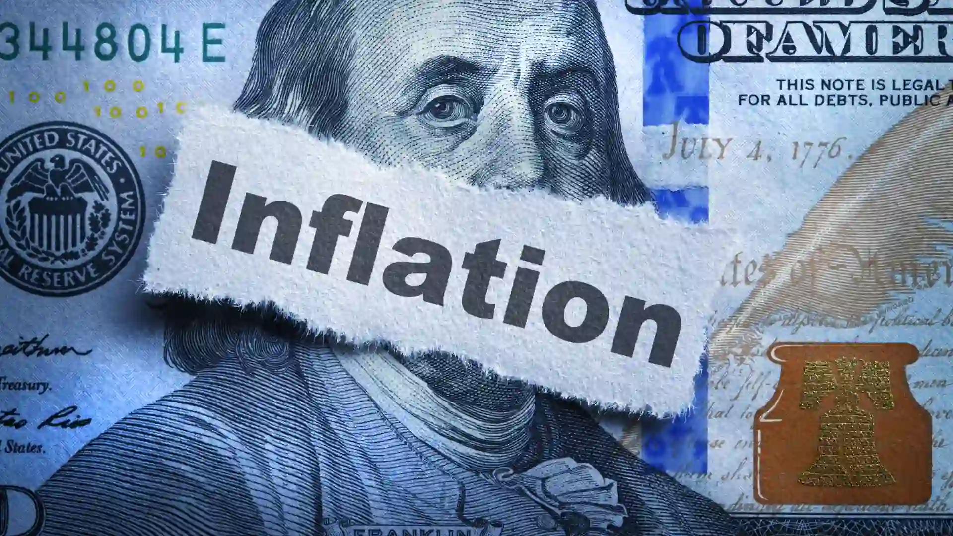 Inflation printed on a piece of torn paper that rests on top of the portrait of Benjamin Franklin on the one hundred dollar bill.