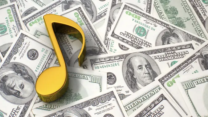Gold music note on the background of one hundred dollar bills.