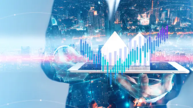 Businessman holding tablet with city hologram show a financial stock market increase profit.