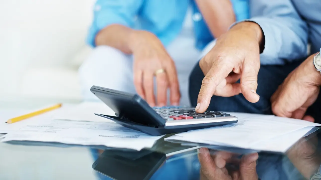 Closeup of old man's hand calculating bills at home stock photo