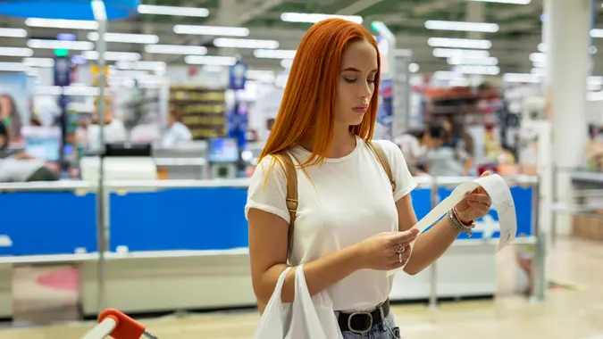 Women shopping at the supermarket and looks at receipt total.