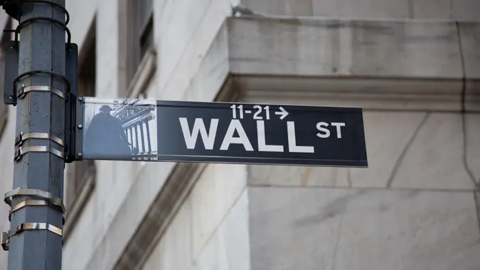 Wall Street Sign with Arrow Pointing towards 11 Wall Street where New York Stock Exchange is, Lower Manhattan Financial District, NY, USA.