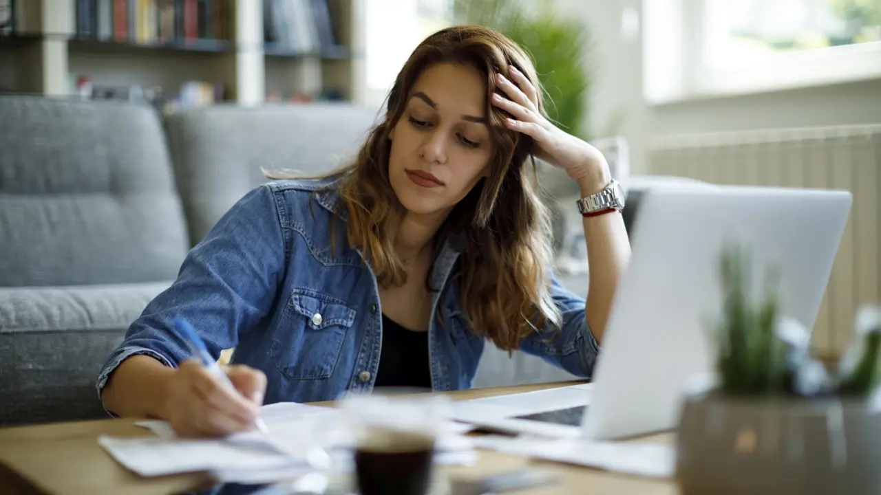 Young worried woman going over finances at home.