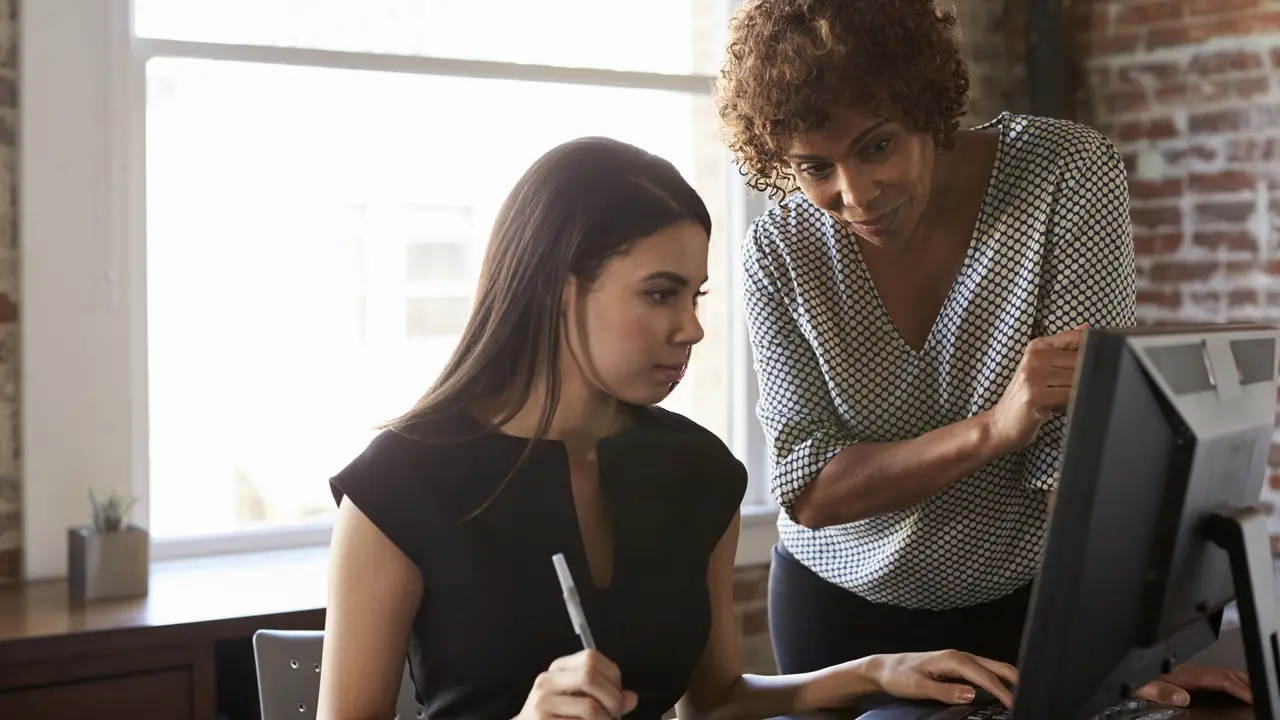 Two Businesswomen Working On Computer In Office.