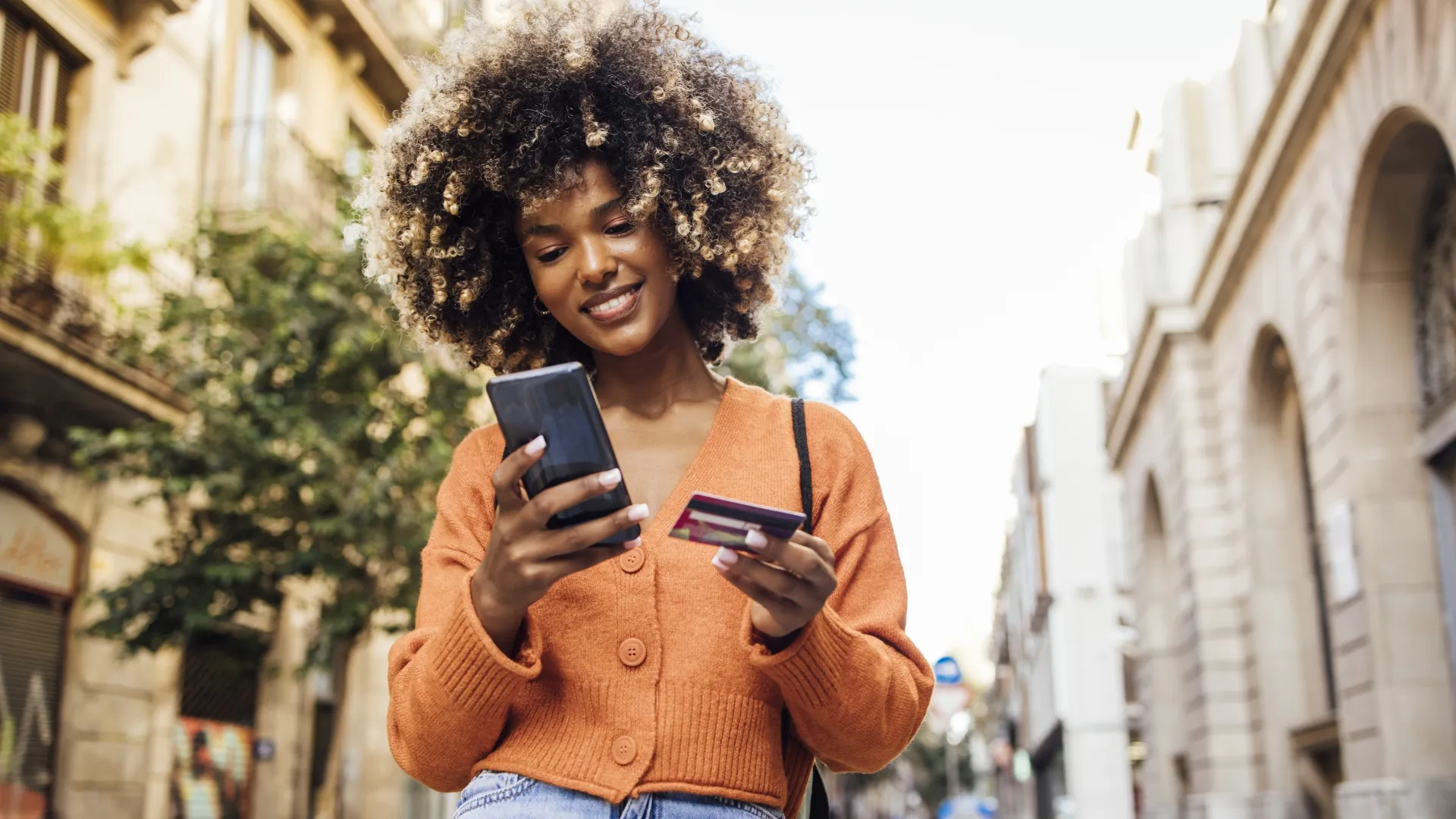 年轻的非洲裔美国妇女的画像在巴塞罗那度假在街上网上购物。