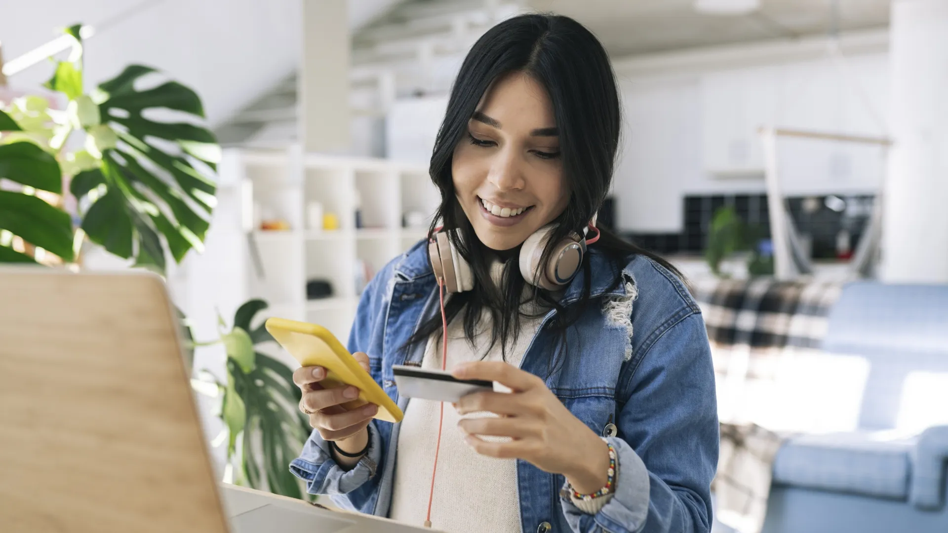 漂亮的西班牙裔妇女在家做网上购物用信用卡和智能手机。