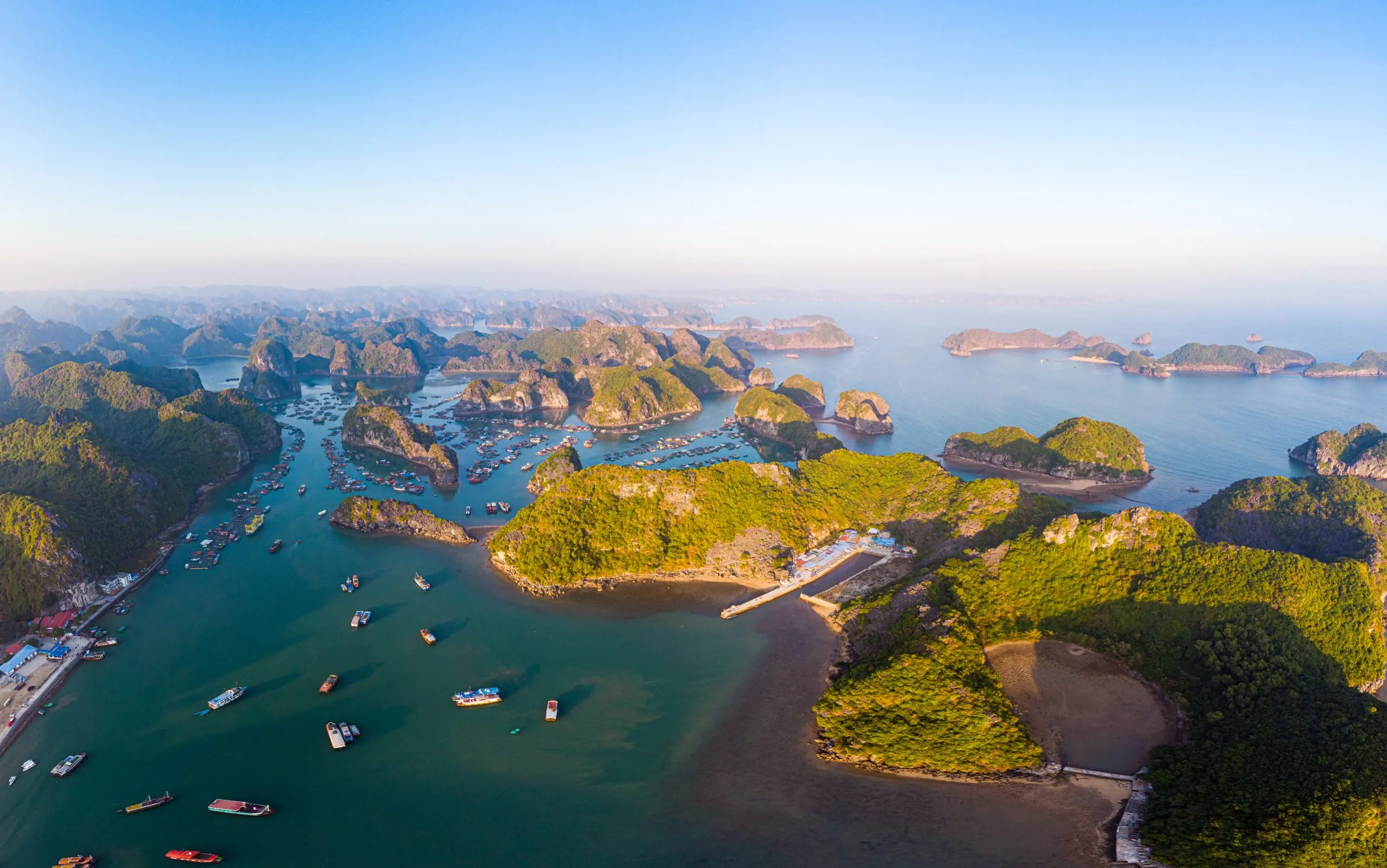 Aerial sunset view of Lan Ha bay and Cat Ba island, Vietnam, unique limestone rock islands and karst formation peaks in the sea, floating fishermen villages and fish farms from above.