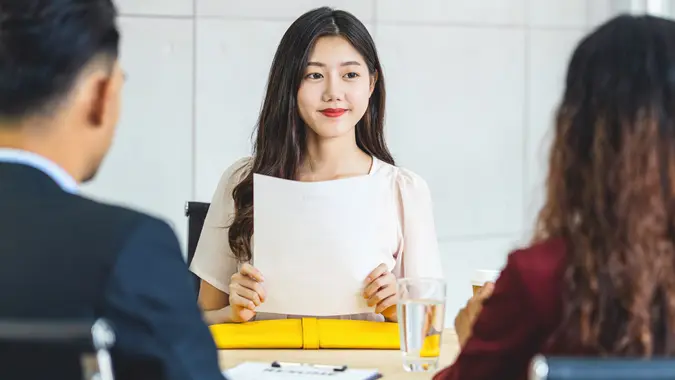 Young Asian woman graduate holding the resume document and preparing to two manager before start to job interview with positive motion in meeting room,Business Hiring new member concept stock photo
