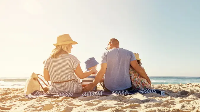 Rearview shot of a family of four sitting on the beachhttp://195.