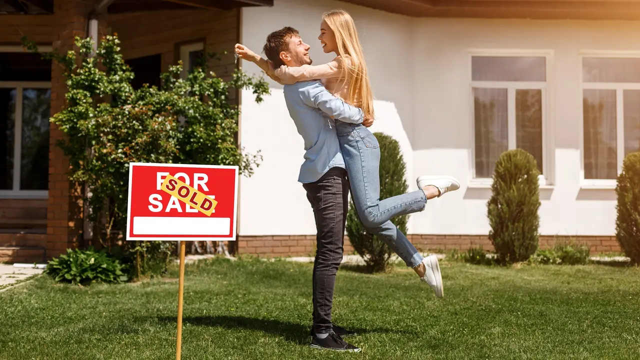 Beautiful young couple hugging in front of their new house, outdoors stock photo