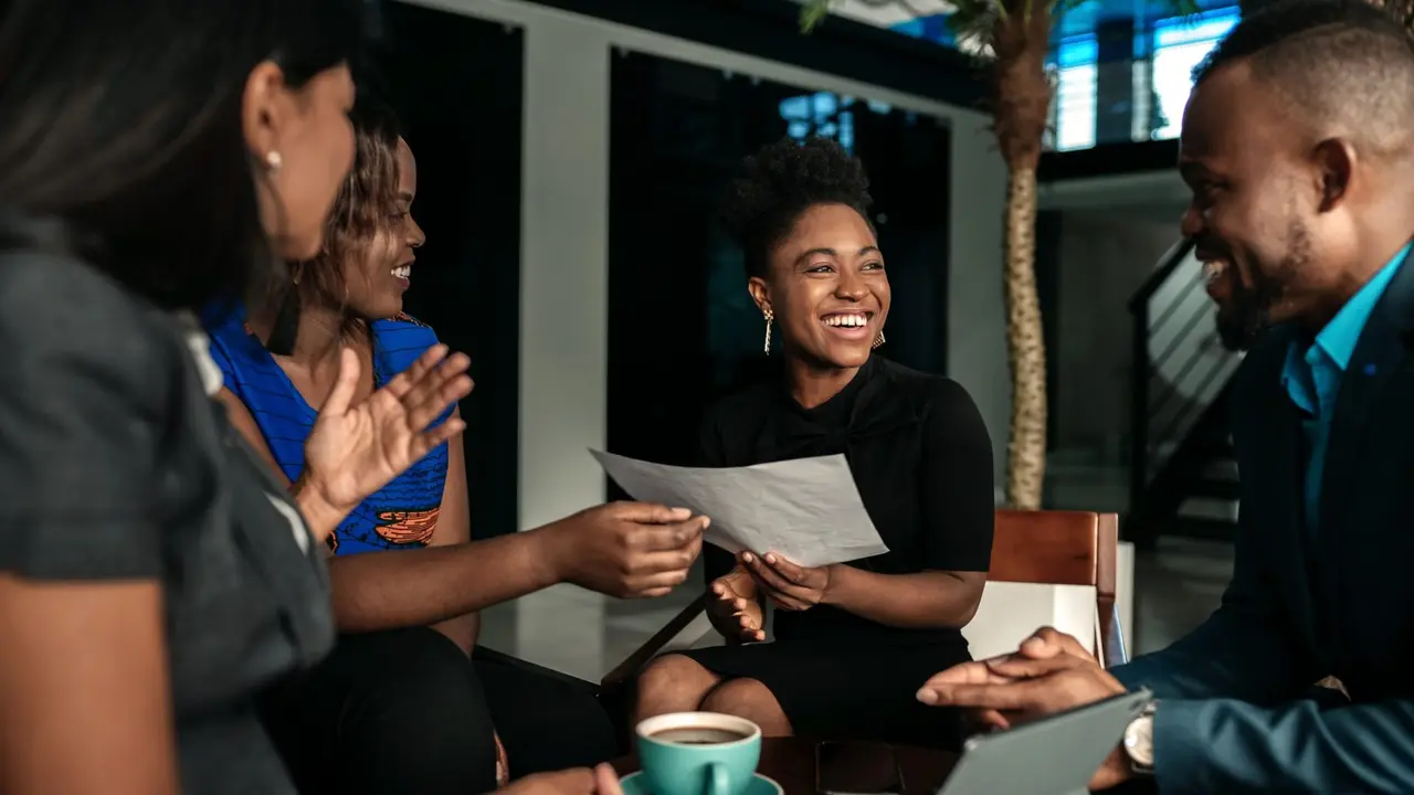 A group of young professionals meeting up and chatting, smiling.