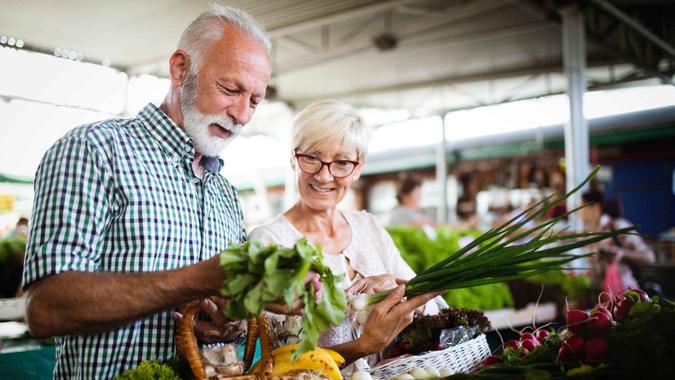 Senior couple shopping vegetables and fruits on the market.