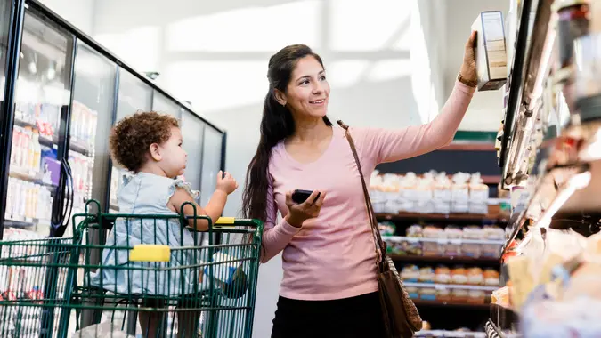 Smiling mother chooses baby's favorite treat at grocery store stock photo