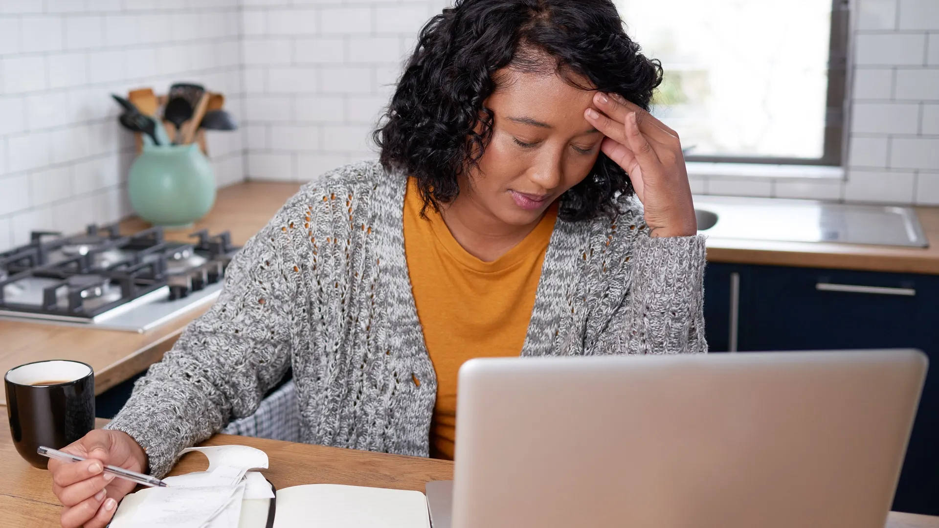 A young multi-ethnic woman is stressed while calculating household expenses stock photo