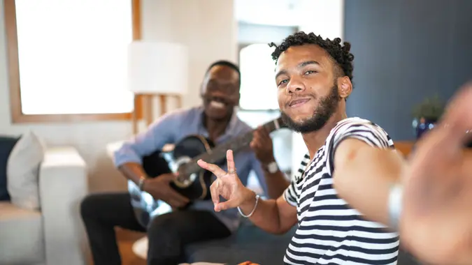 Selfie of father and son playing music in living room.