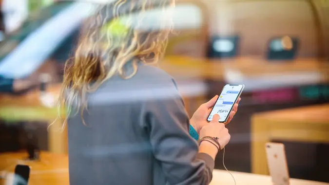 View from the street of Woman holding latest iPhone X inside Apple Store stock photo