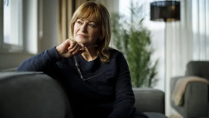 Portrait of worried senior woman sitting on sofa at home stock photo
