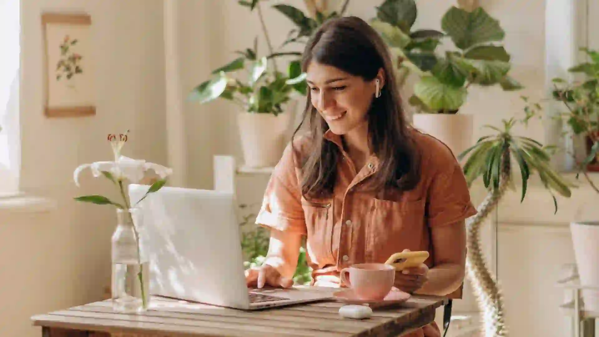 Positive young mixed race woman using a laptop and smartphone at home.