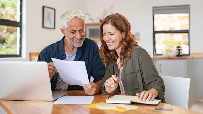 Mature smiling couple sitting and managing expenses at home.