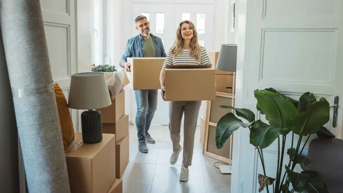 Mature couple moves in to their new home, unpacking boxes and enjoying the time together.