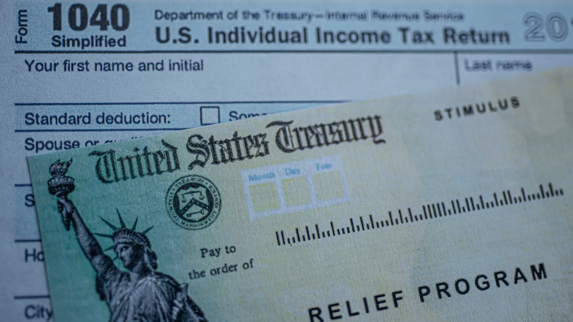 Form 1040 U.S. Individual Income tax return next to the Stimulus Check Relief program. Close up view. stock photo