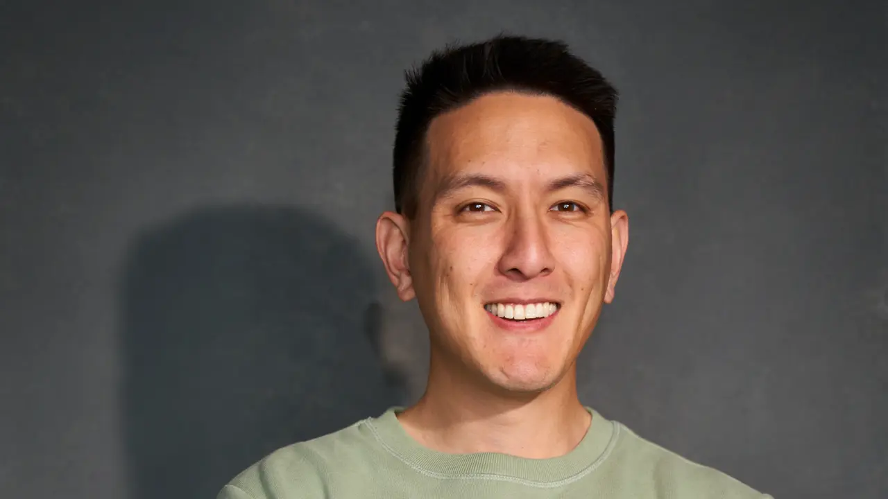 Humphrey Yang smiling in front of a grey backdrop