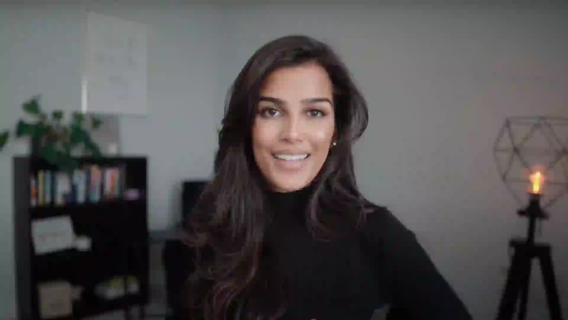 Nischa wearing a black turtleneck and smiling at the camera