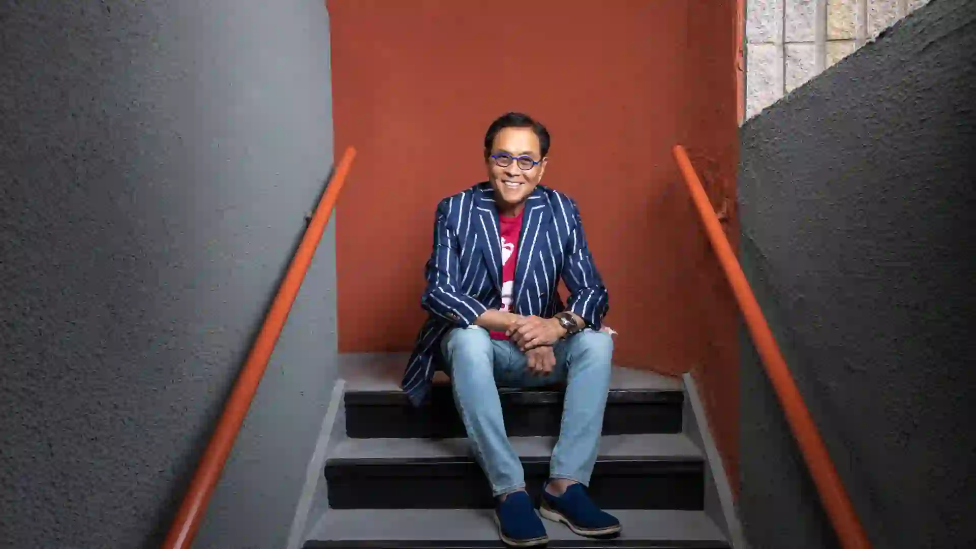 Robert Kiyosaki smiling and sitting on steps