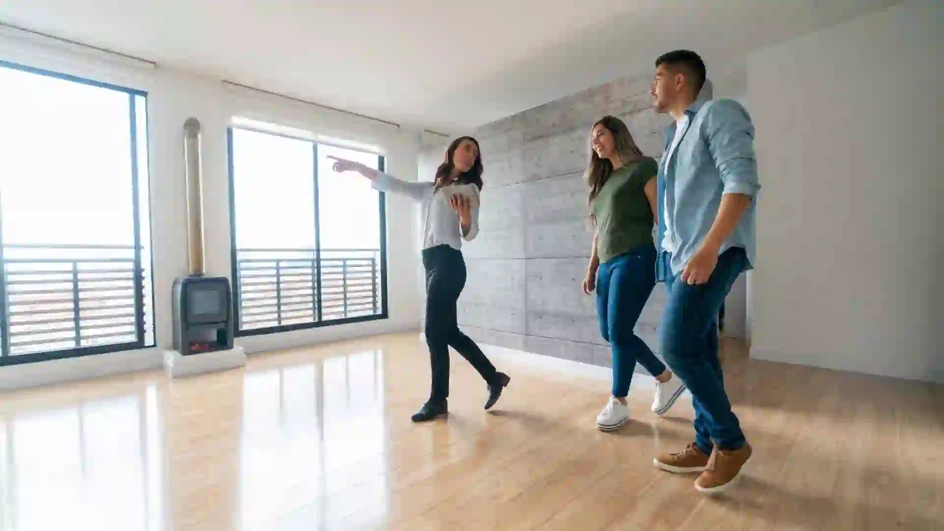 Real estate agent showing a house for sale to a happy couple  - home ownership concepts.