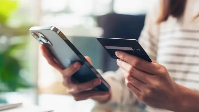 Woman hand holding credit cards and using smartphone for shopping online with payment on internet banking.