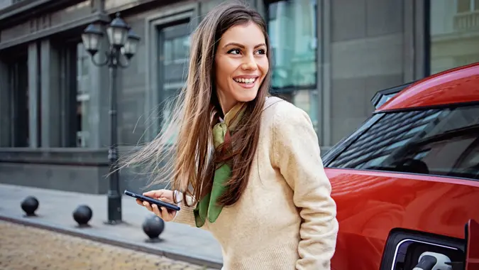 Portrait of woman charging her electric car.