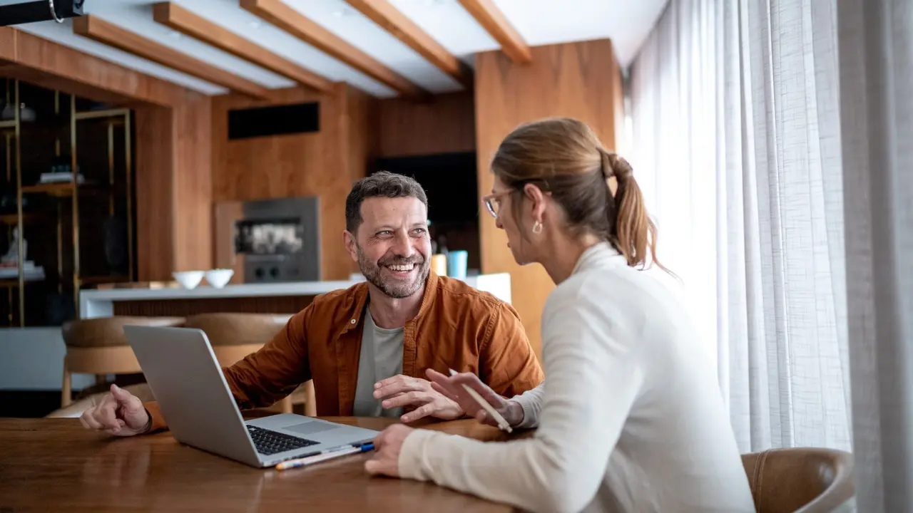 Mature couple talking and using the laptop at home.