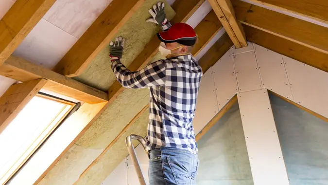 Man installing thermal roof insulation layer - using mineral wool panels. Attic renovation and insulation concept stock photo