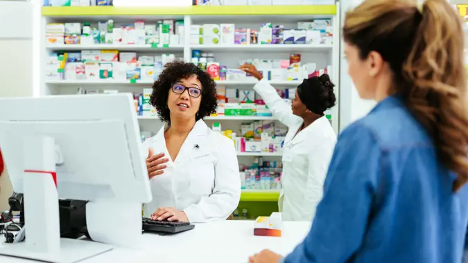 A pharmacist is having a friendly talk with one of the regular customers at the pharmacy.