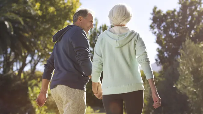 Senior couple holding hands and walking in park stock photo